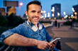 © Bartek Szewczyk/Westend61 - Portrait of a smiling man using his smartphone while sitting on a bench in the evening