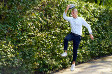 Happy Young Man Jumping Around At A Hedge