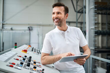 Smiling Man Using Tablet At Control Panel In A Factory