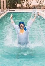 Man With Blue Turban Splashing Water In A Swimming Pool