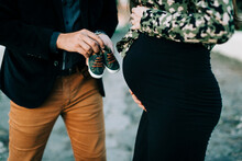 Close-up Of Expectant Parents Holding Baby Shoes