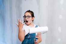 Shocked Girl Looking At Her Stained Hand While Painting A Wall In A House
