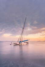 Spain, Murcia, Santiago De La Ribera, Abandoned Sailboat On Calm Sea At Sunset