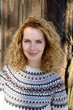 Blonde woman with curly hair smiling, norwegian sweater