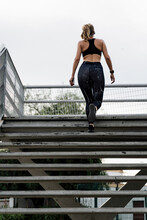 Sporty Woman Climbing Stairs On A Bridge, Rear View