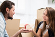 © Eloisa Ramos/Westend61 - Man handing over tiny house model to girlfriend surrounded by cardboard boxes