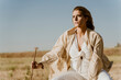 © Eloisa Ramos/Westend61 - Female traveller sitting on stool, meadow