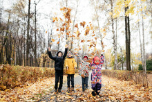 Group Of Four Kids Playing With Autumn Leaves