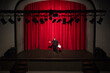 © Francesco Buttitta/Westend61 - Rehearsing actor with script standing on theatre stage in front of red curtain