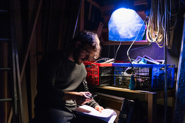 Man with script sitting backstage at theatre looking at cell phone