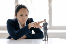 Businesswoman Watching Businessman Figurine, Standing On Her Desk