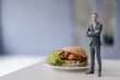 © Westend61 - Miniature businessman figurine standing next to fast food