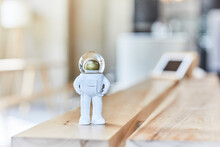 Miniature Astronaut Figurine On Wooden Bench