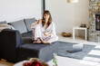 © Jo Kirchherr/Westend61 - Portrait of smiling woman having breakfast on couch at home