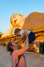 Myanmar, Mon State, Mother Holding Baby Girl In Front OfÔøΩgiant Statue Of Reclining Buddha In Pupawadoy Monastery