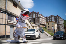 Large Toy Dinosaur With Bread Walking On Zebra Crossing In City