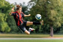 Young Woman Playing Soccer In Field