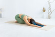 © Вадим Каштанов - Woman in light green sportswear practices yoga. Balasana pose. child's pose.