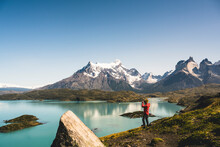 Man Looking At Lake Pehoe Through Binocular In Torres Del Paine National Park, Chile Patagonia, South America