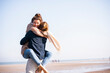 © Uwe Umst√§tter/Westend61 - Happy young woman embracing boyfriend at beach against clear sky on sunny day