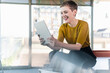 © UWE_UMSTAETTER/Westend61 - Happy businesswoman sitting on desk in office using tablet