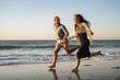 © Uwe Umst√§tter/Westend61 - Cheerful young couple holding hands while running at beach during sunset