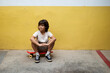 © VALENTINA BARRETO PHOTOGRAPHY/Westend61 - Thoughtful boy sitting on skateboard against wall