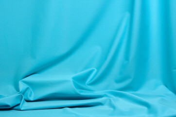 Textured background made of soft blue fabric with elegant pleats.