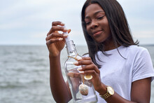 Portrait Of Young Woman In Front Of The Sea Sending Message In A Bottle