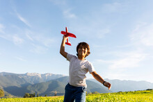 Smiling Boy Holding Airplane Toy While Standing Against Clear Sky