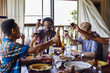 © victor espadas/Westend61 - Smiling male and female friends toasting drinks while sitting at dining table during lunch