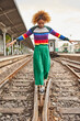 © victor espadas/Westend61 - Full length of young woman with afro hairstyle walking on tracks at station against sky