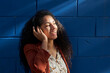© Veam/Westend61 - Woman wearing headphones looking away while standing against blue wall