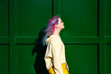 Portrait Of Young Woman With Dyed Hair In Front Of Green Container