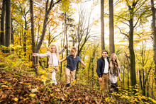 Boy And Girl Enjoying By Parents In Forest During Autumn