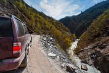 Georgia, Svaneti, Ushguli, 4x4 Car Driving Along Mountain Road Overlooking River Flowing Along Forested Valley