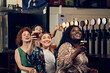 © Dangubic/Westend61 - Excited female friends sitting at the counter in a pub watching Tv