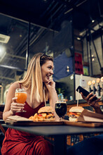 Happy Woman With Friend In A Pub Having A Beer And A Burger