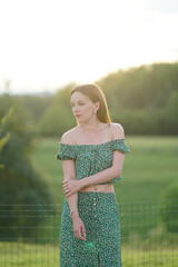 Poster - Young attractive caucasian female in a green two-piece outfit posing outdoors