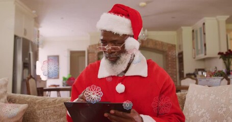 Canvas Print - Animation of snow falling over african american man holding clipboard at christmas