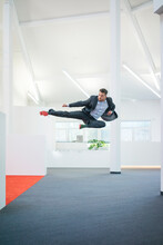 Businessman Jumping Mid-air On Office Floor