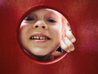 © Frank Muckenheim/Westend61 - Portrait of smiling little boy looking through hole on playground