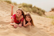 © Nicole Matthews/Westend61 - Portrait of two smiling girls lying on the beach