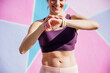 © Jose Luis CARRASCOSA/Westend61 - Smiling sportswoman looking on smartwatch, colorful wall in the background