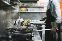 Chef preparing a dish at gas stove in restaurant kitchen