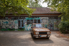 Germany, Berlin, Brown Vintage Car Parked In Front Of Building Covered In Graffiti