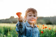 © JOSEP M ROVIROSA/Westend61 - Boy in a poppy field in spring holding poppy