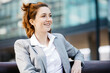 © JOSEP M ROVIROSA/Westend61 - Young businesswoman sitting on a bench in the city, smiling