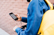 © JOSEP M ROVIROSA/Westend61 - Man with backpack and E-Scooter using navigation app on his mobile phone, partial view