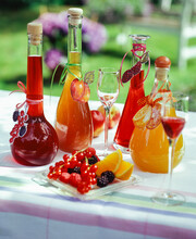 Homemade Fruit Liqueurs In Carafes On Garden Table